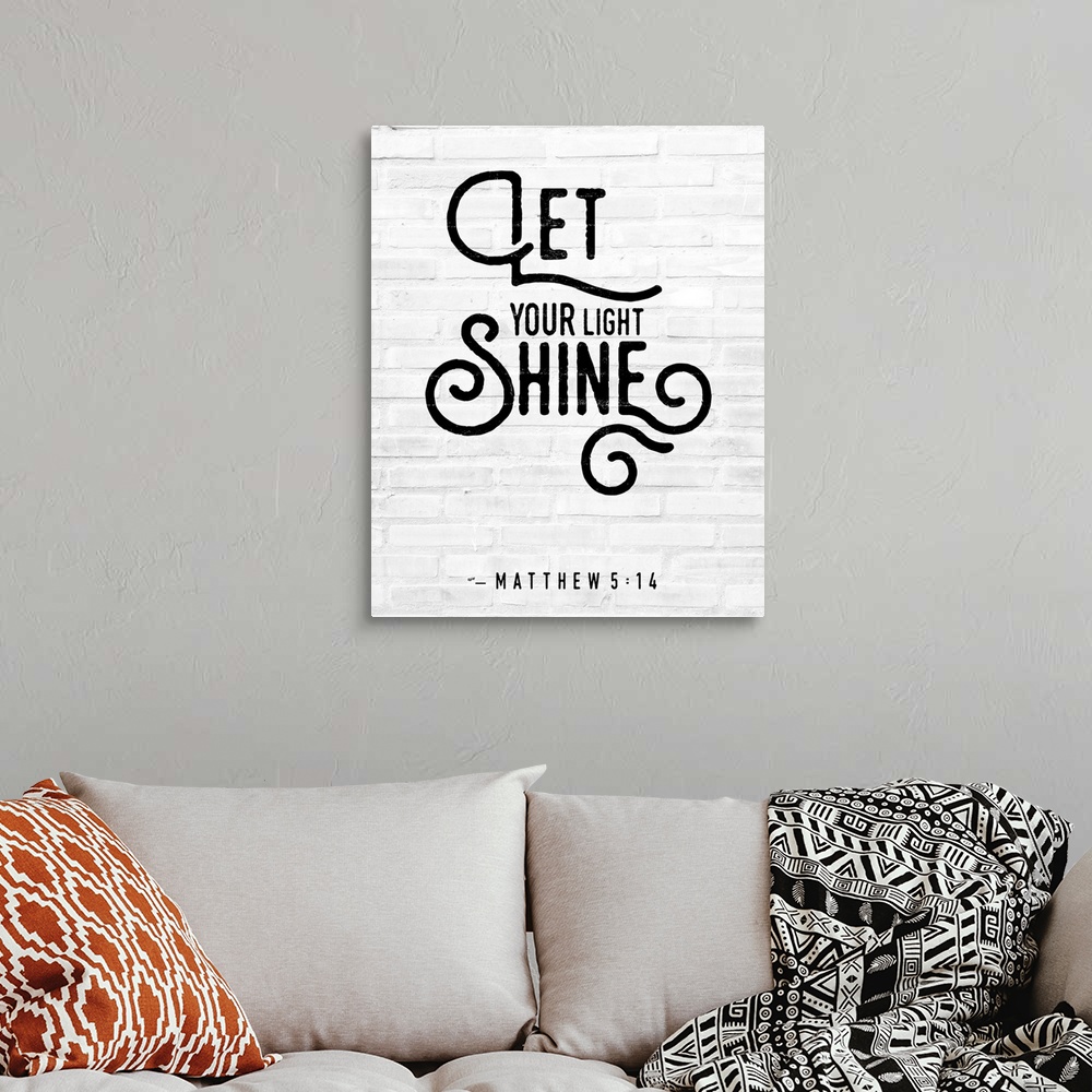 A bohemian room featuring A Bible Verse stating 'Let your Light Shine' in a modern black font against a faux white brick ba...