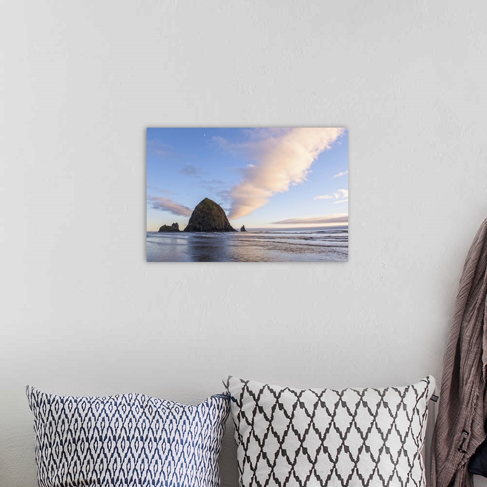 A bohemian room featuring Photograph of Haystack Rock at sunset with rippling waters in the foreground and the moon above.