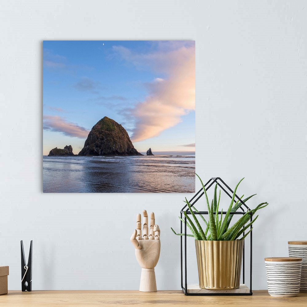 A bohemian room featuring Square photograph of Haystack Rock at sunset with rippling waters in the foreground and the moon ...
