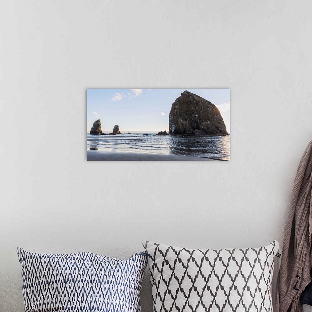A bohemian room featuring Panoramic photograph of Haystack Rock at Cannon Beach with blue skies.