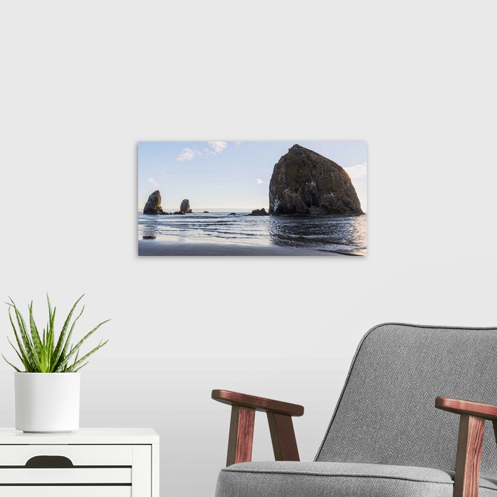 A modern room featuring Panoramic photograph of Haystack Rock at Cannon Beach with blue skies.