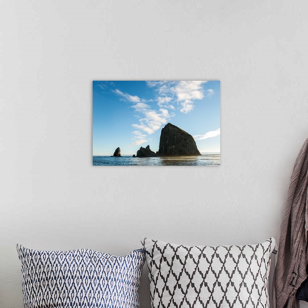 A bohemian room featuring Photograph of Haystack Rock with the golden sun shining on its side and the moon in the top corner.