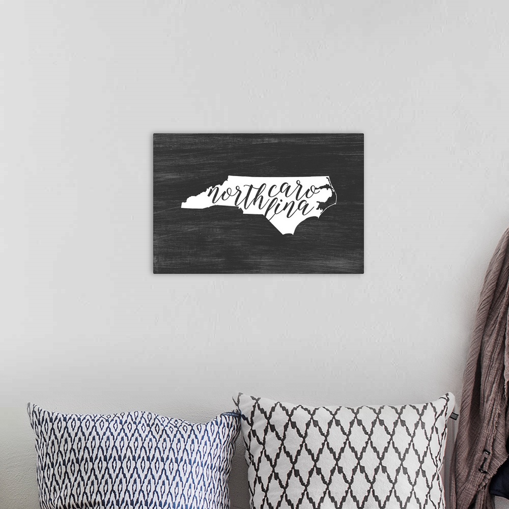 A bohemian room featuring North Carolina state outline typography artwork.