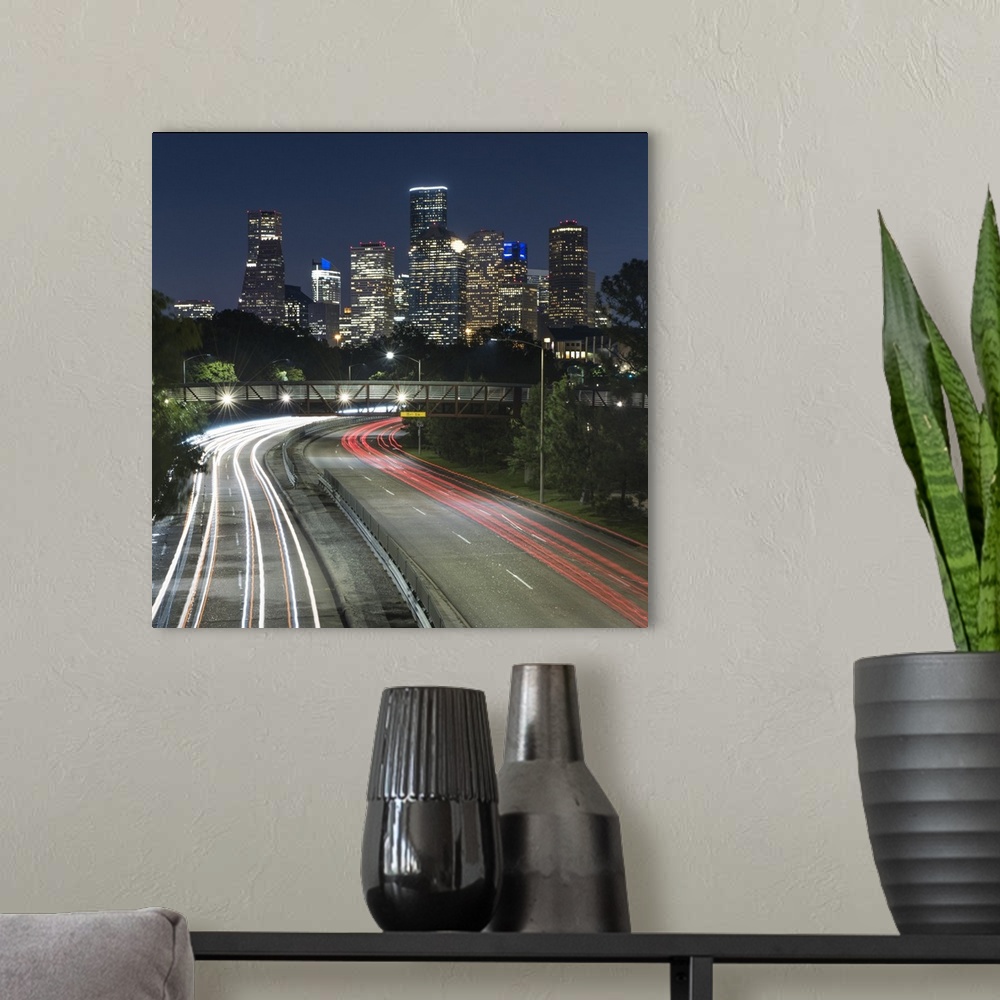 A modern room featuring Square photograph of the Houston, TX skyline at night with curving light trails from cars driving...