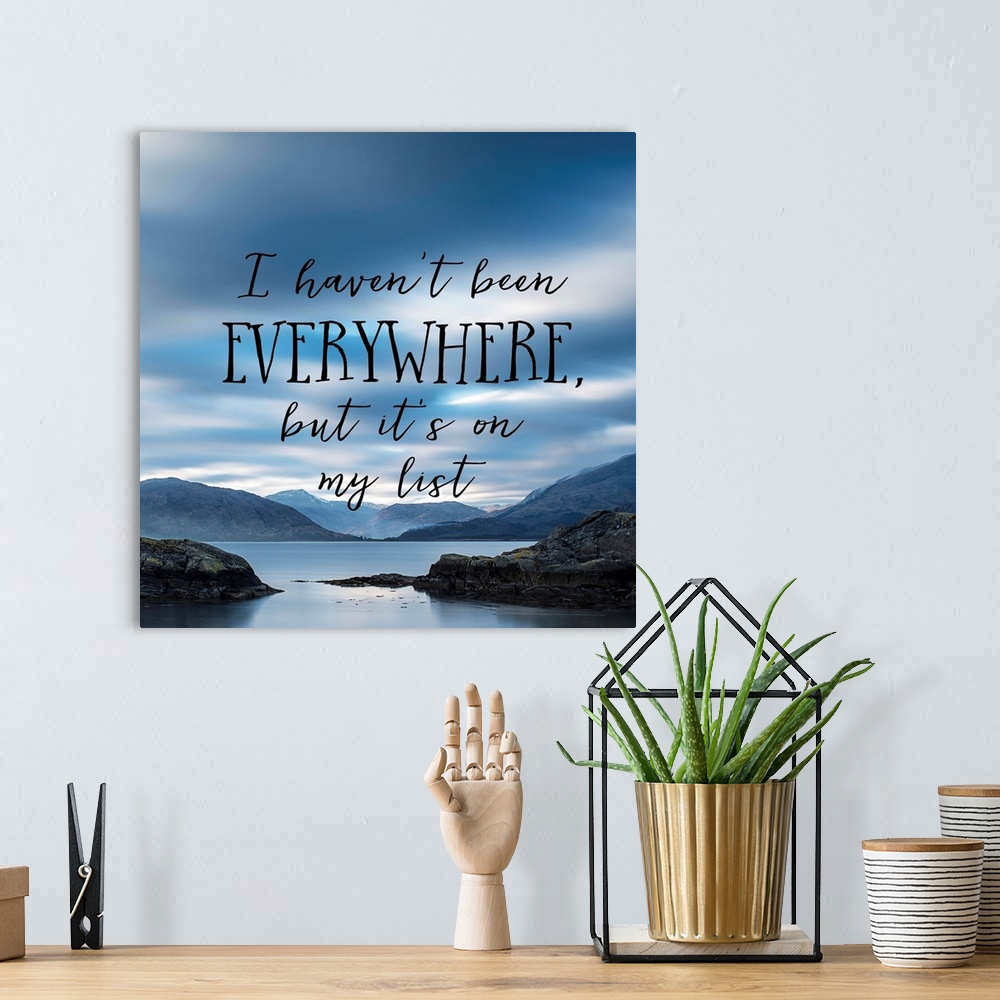 A bohemian room featuring Black text reading "I haven't been everywhere, but it's on my list" over an image of a misty bay ...