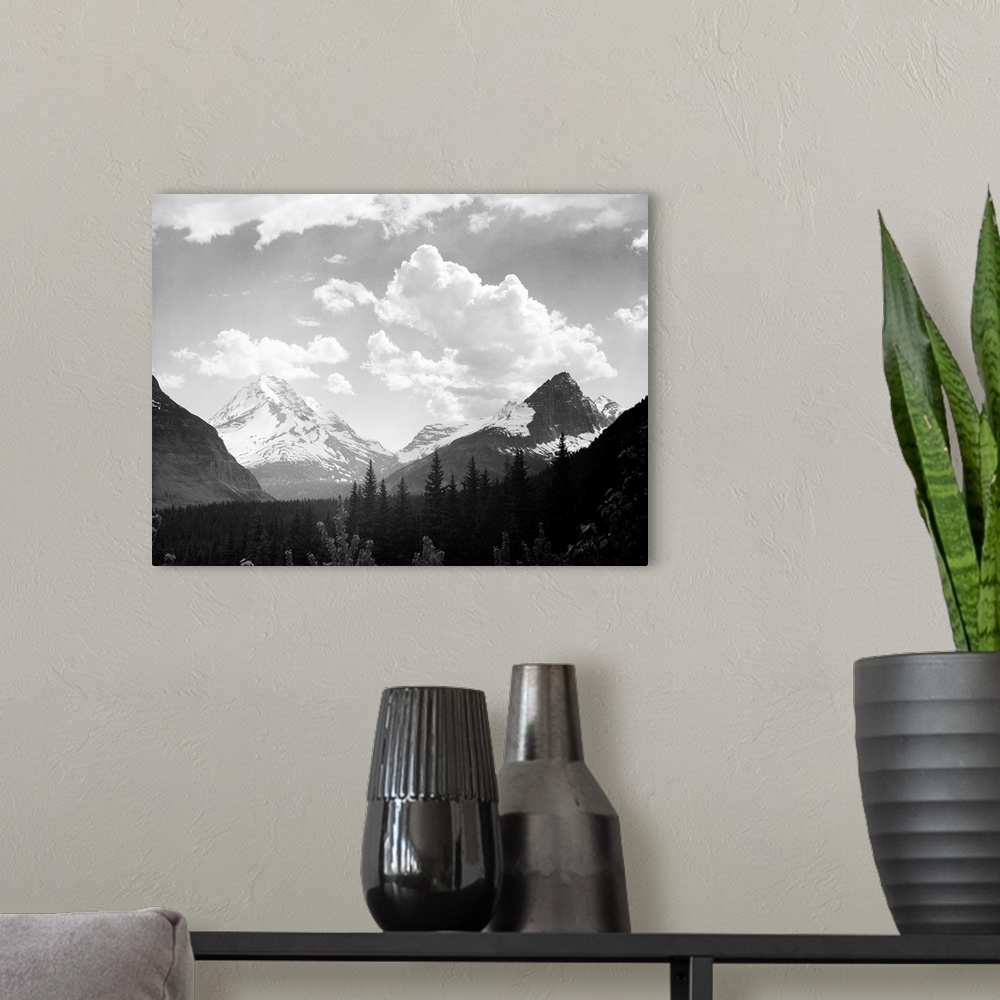 A modern room featuring In Glacier National Park, looking across forest to mountains and clouds.