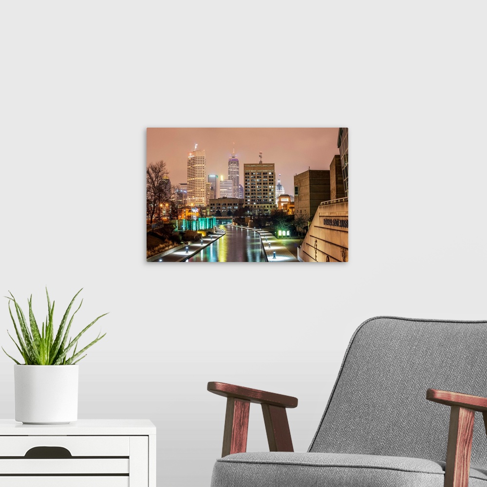 A modern room featuring Photo of the Indianapolis city skyline at night reflecting onto the Indiana Central Canal.