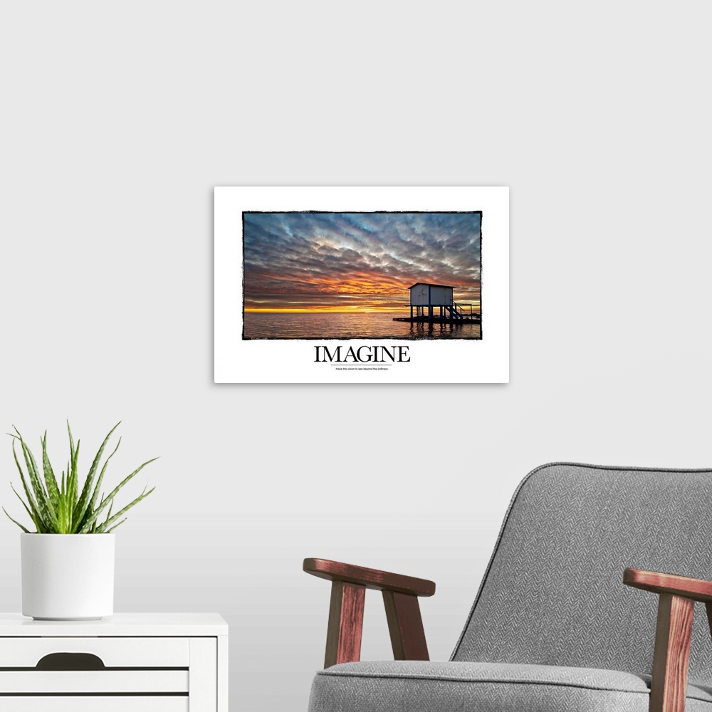 A modern room featuring Inspirational artwork of a sunset sky over a vast ocean with a tiny hut that sits in it and under...