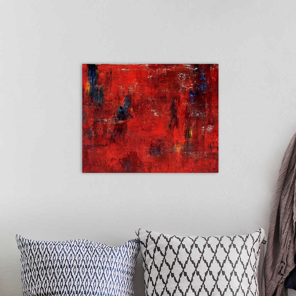 A bohemian room featuring Abstract painting featuring shades of red and maroon with swipes of blue and yellow.