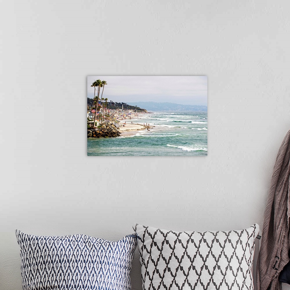 A bohemian room featuring Landscape photograph of the La Jolla coast filled with beach goers and palm trees.