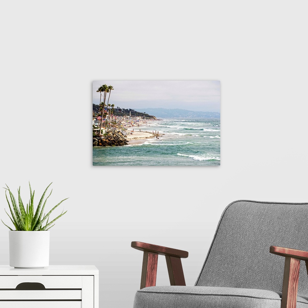 A modern room featuring Landscape photograph of the La Jolla coast filled with beach goers and palm trees.