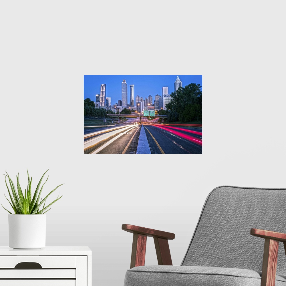A modern room featuring Bright light trails from traffic on the freeway, headed towards the Atlanta, Georgia skyline at t...