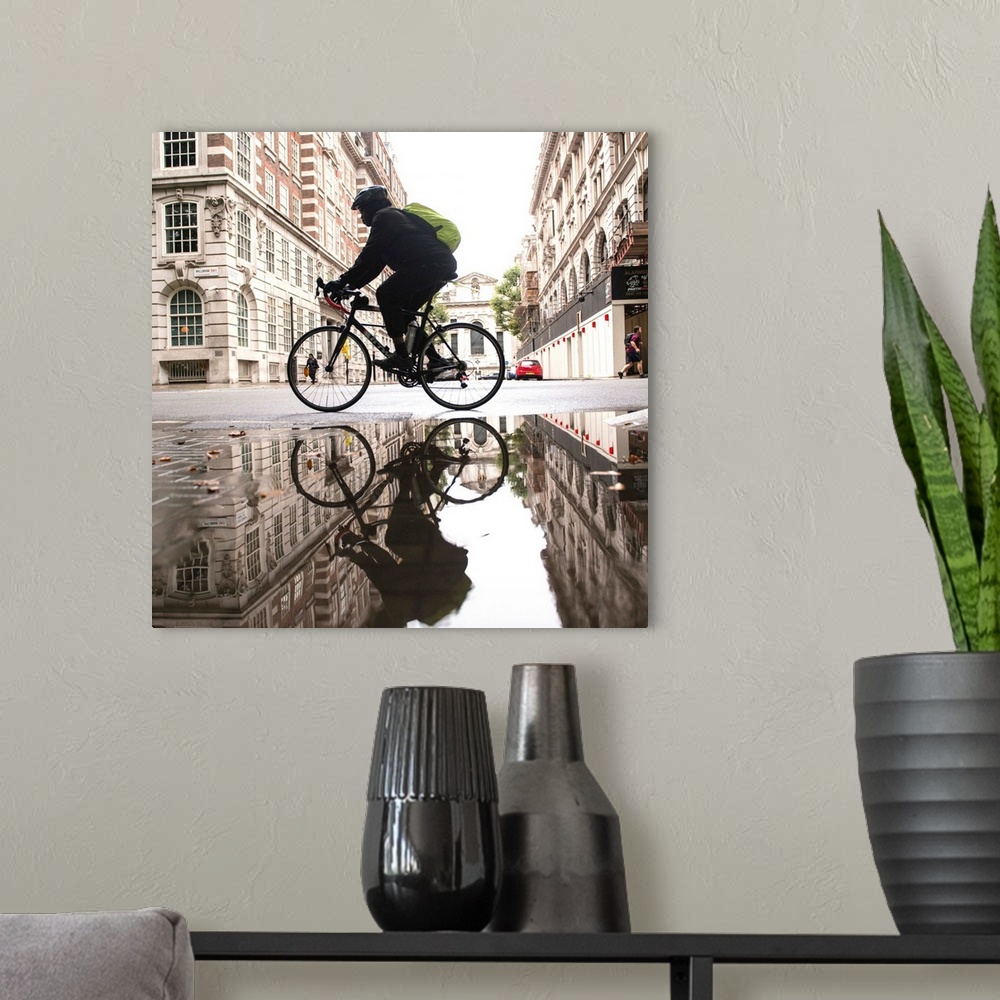 A modern room featuring Square photograph of a biker reflecting into a puddle in London, England.