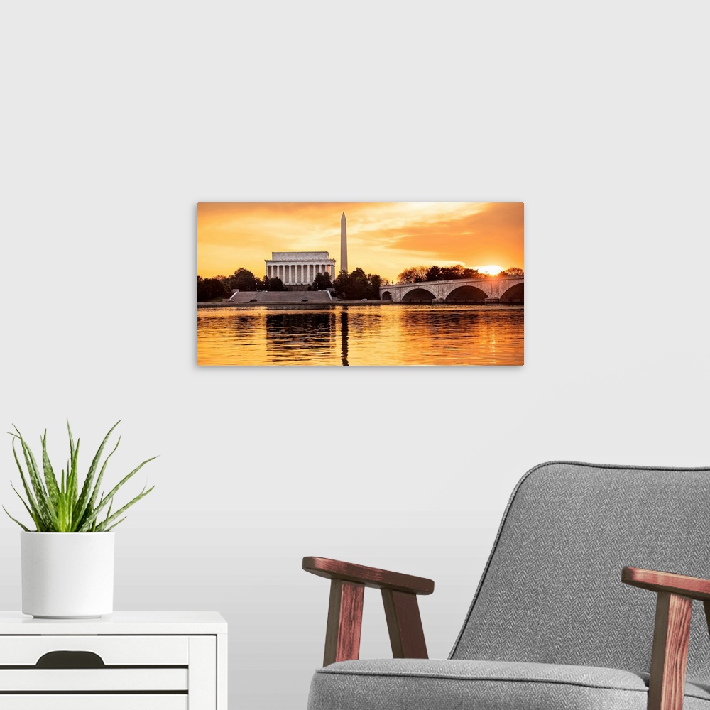 A modern room featuring The Lincoln Memorial and Washington Monument seen from the Potomac River with orange clouds at dusk.