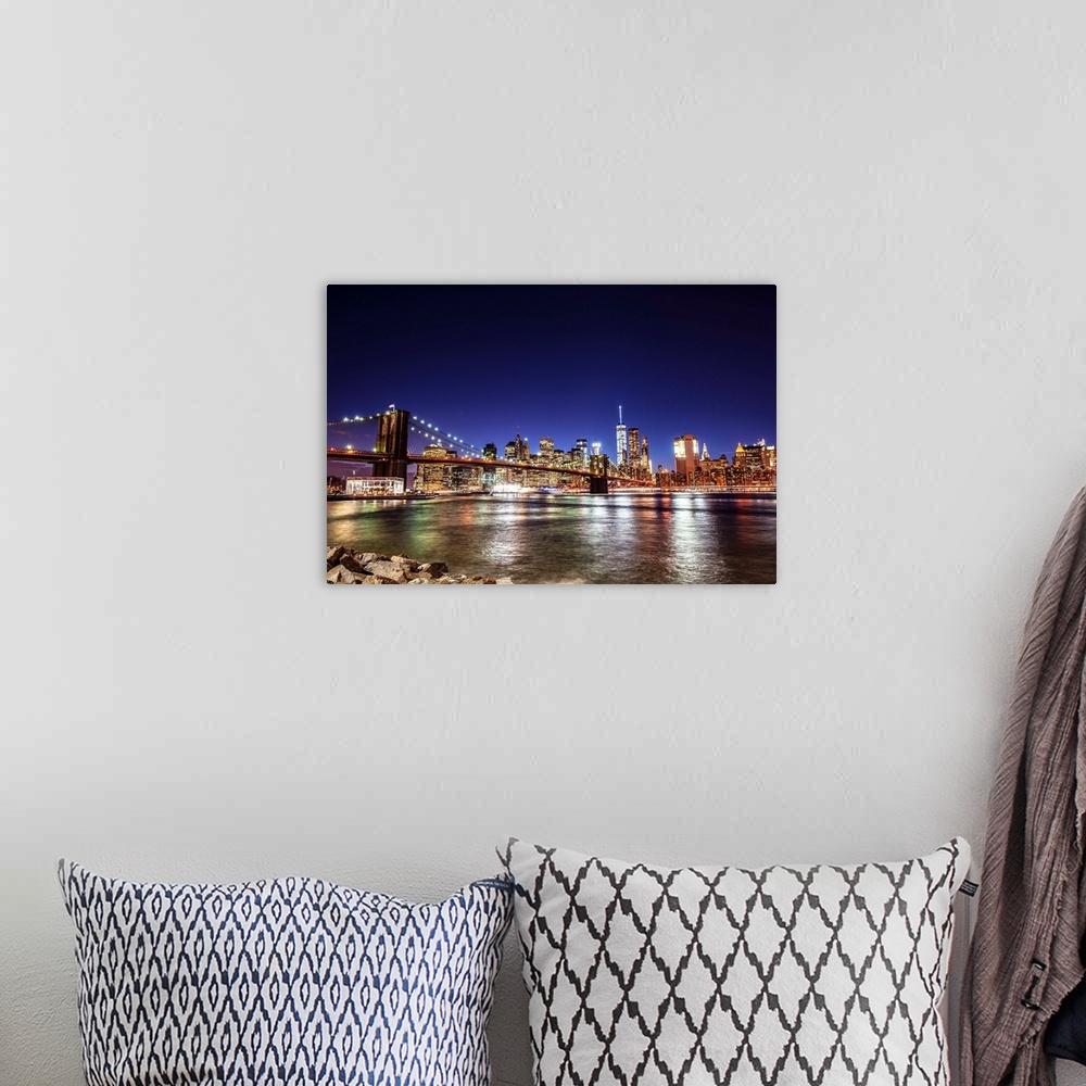 A bohemian room featuring View of the New York City skyline illuminated at night, with the Brooklyn Bridge, from across the...