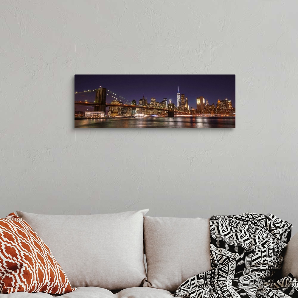 A bohemian room featuring View of the New York City skyline illuminated at night, with the Brooklyn Bridge, from across the...