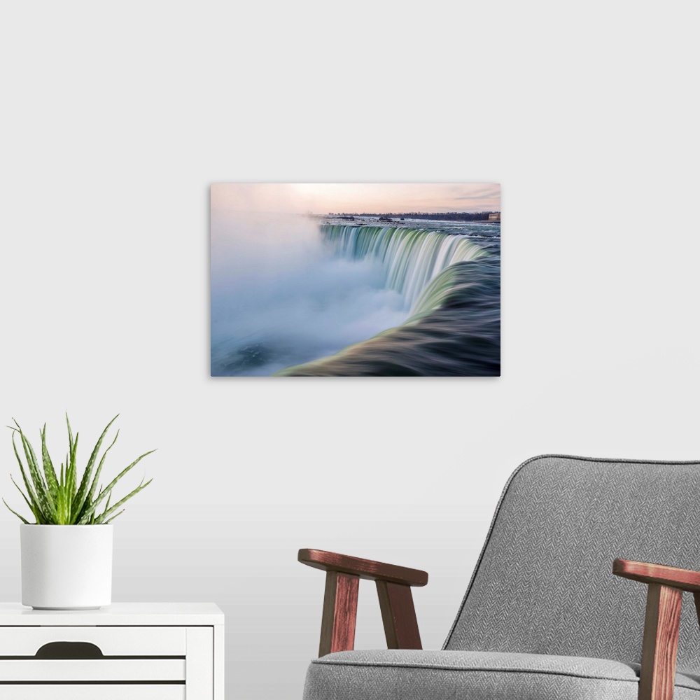A modern room featuring Water cascades down at Horseshoe Falls while dramatic mist ascents to meet the rising sun.