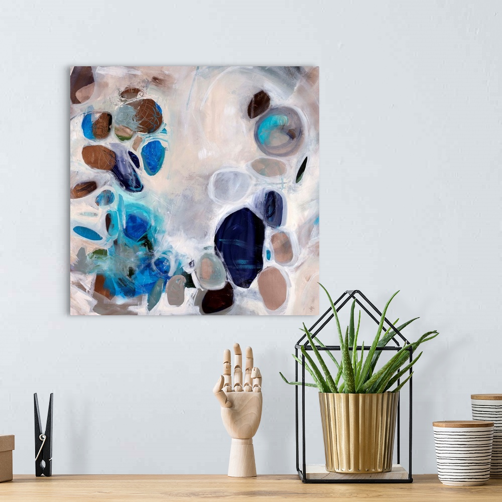 A bohemian room featuring Contemporary abstract painting of stone-like shapes in blues and browns over a neutral background.