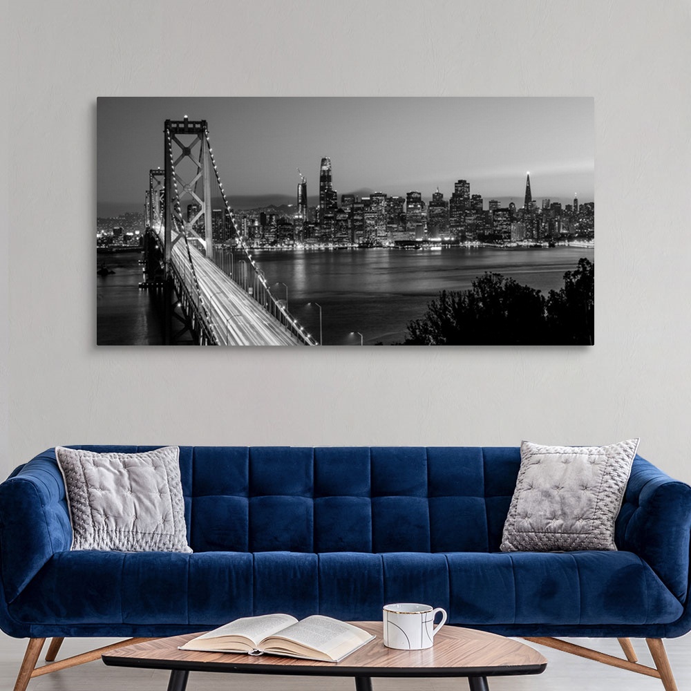 A modern room featuring Photograph of the Bay Bridge with a sunset and the San Francisco skyline lit up in the background.