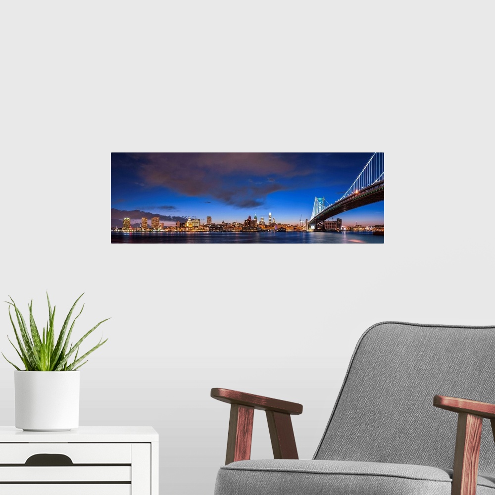 A modern room featuring Panoramic view of Philadelphia city skyline at night with Ben Franklin Bridge.