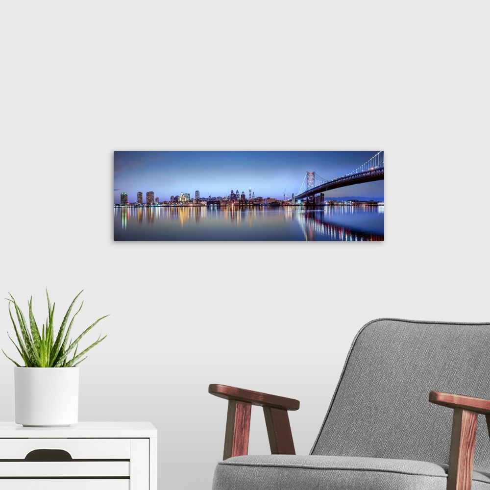 A modern room featuring Panoramic photo of the Philadelphia city skyline reflected in the water at night, with the Benjam...