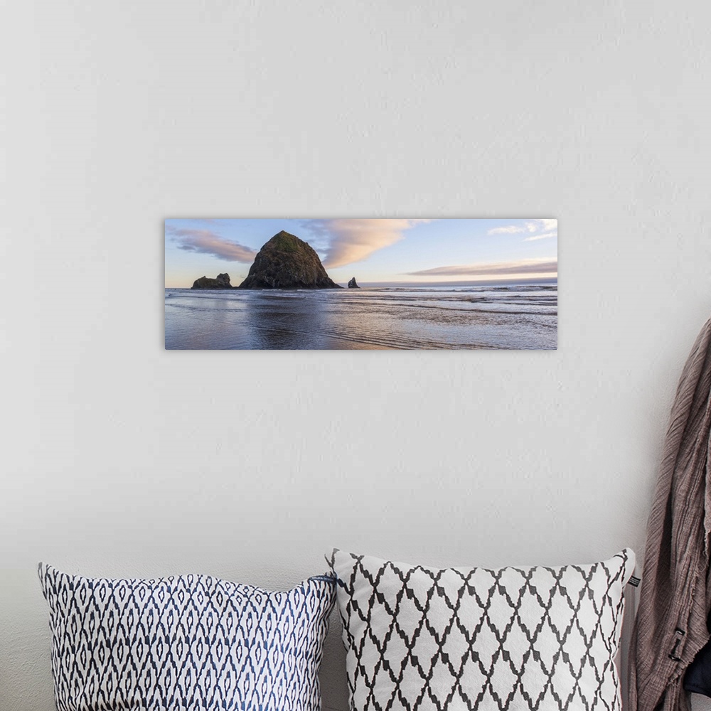 A bohemian room featuring Panoramic photograph of Haystack Rock with a pink and purple sunset and reflections on the water.