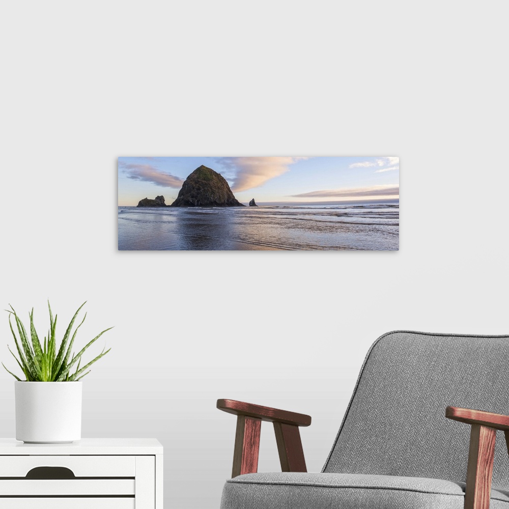A modern room featuring Panoramic photograph of Haystack Rock with a pink and purple sunset and reflections on the water.