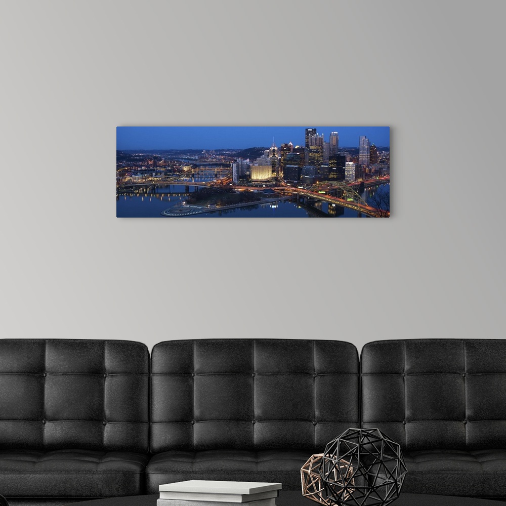 A modern room featuring Panoramic photo of the city of Pittsburgh illuminated at night, with Point State Park in the fore...