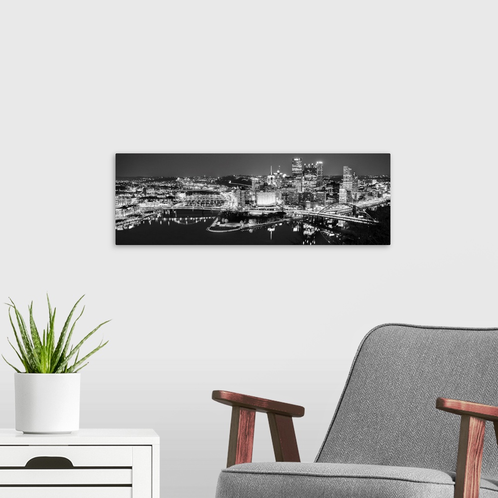 A modern room featuring Panoramic photo of the city of Pittsburgh illuminated at night, with Point State Park in the fore...