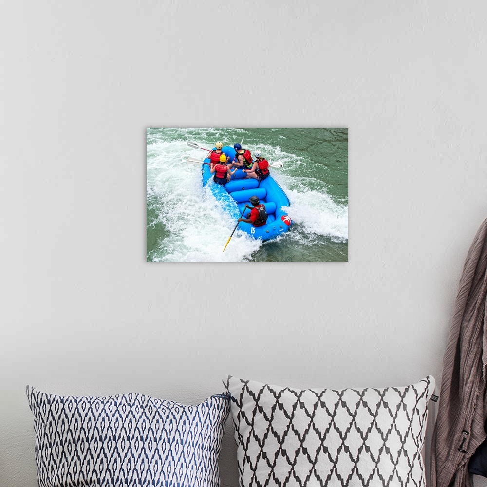 A bohemian room featuring A raft filled with people float in whitewater rapids.
