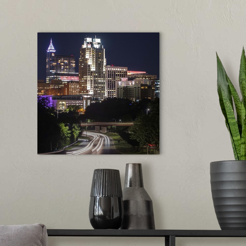 A modern room featuring Skyscrapers in Raleigh illuminated at night, seen from McDowell Street, North Carolina.