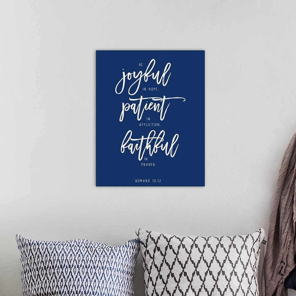A bohemian room featuring Handlettered Bible verse reading Be joyful in hope, patient in affliction, faithful in prayer.