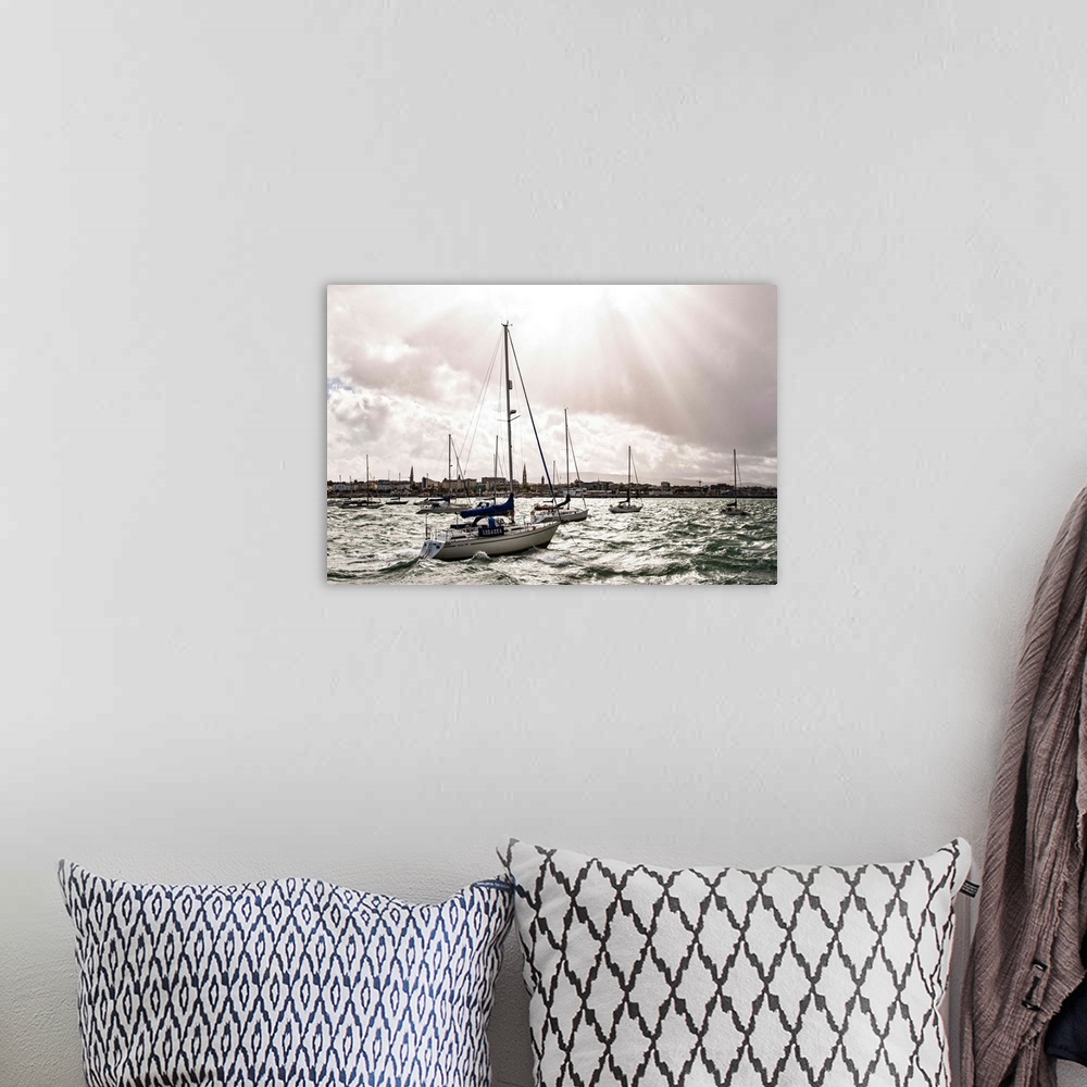 A bohemian room featuring Photograph of the sun peaking through the clouds over the River Liffey in Ireland, and sailboats ...