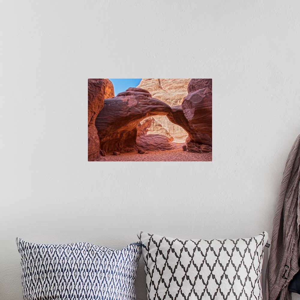 A bohemian room featuring Sunlight illuminates the red sandstone of the Sand Dune Arch and the sandy trail below, Arches Na...
