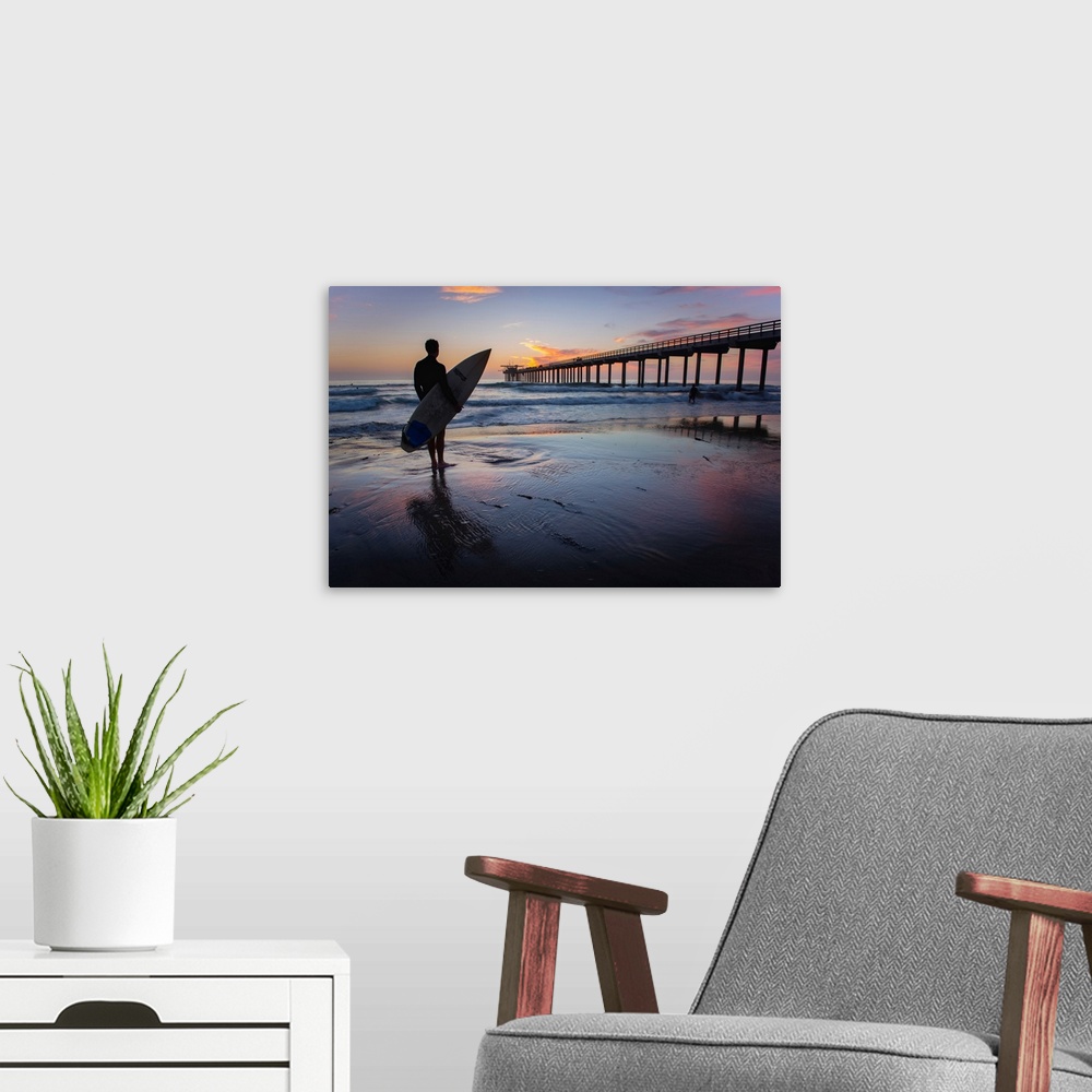 A modern room featuring Silhouetted photograph of a man holding a surf board on the shore of Ocean Beach in San Diego, Ca...