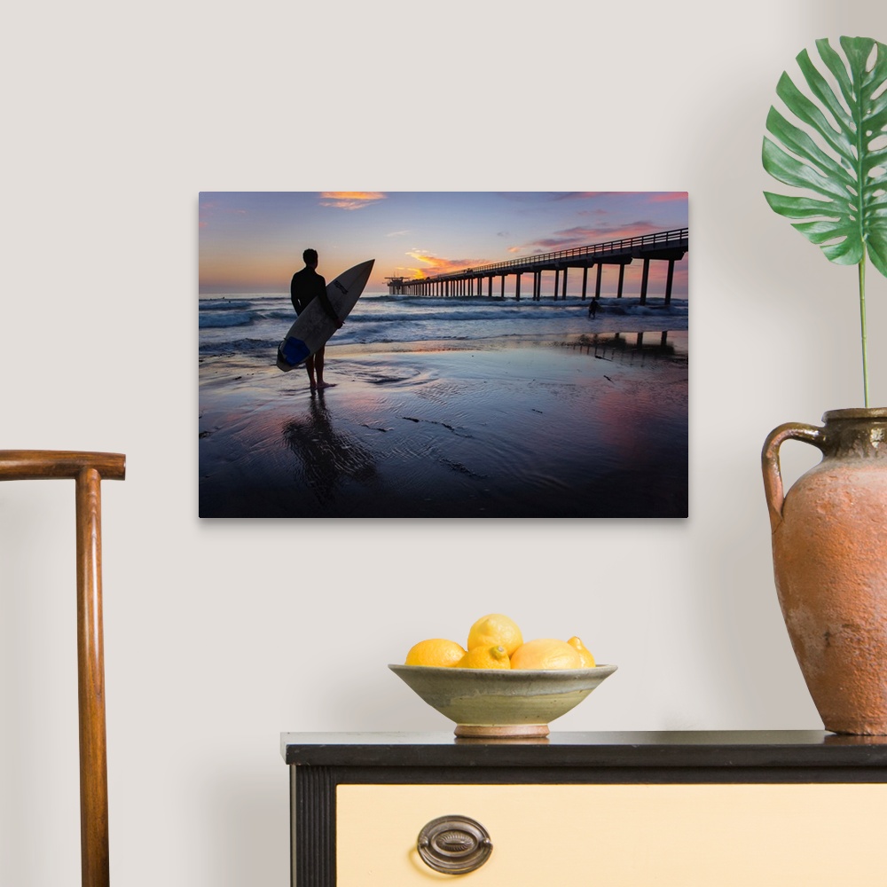 A traditional room featuring Silhouetted photograph of a man holding a surf board on the shore of Ocean Beach in San Diego, Ca...