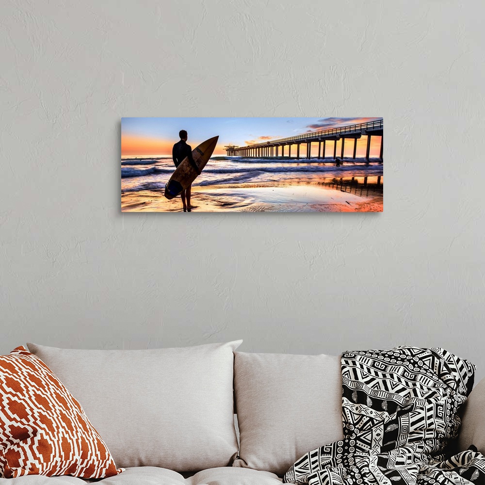 A bohemian room featuring Silhouetted panoramic photograph of a man holding a surf board on the shore of Scripps Beach in S...