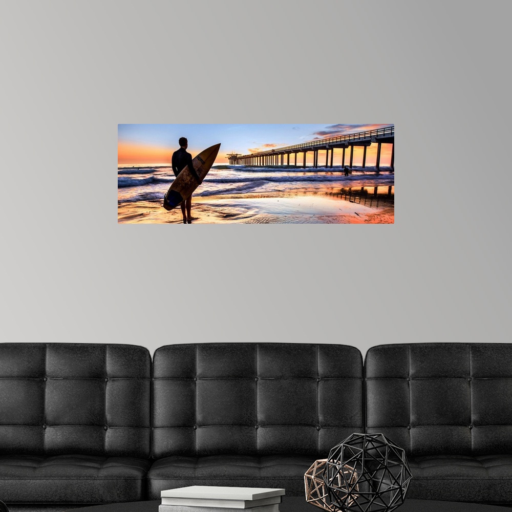 A modern room featuring Silhouetted panoramic photograph of a man holding a surf board on the shore of Scripps Beach in S...