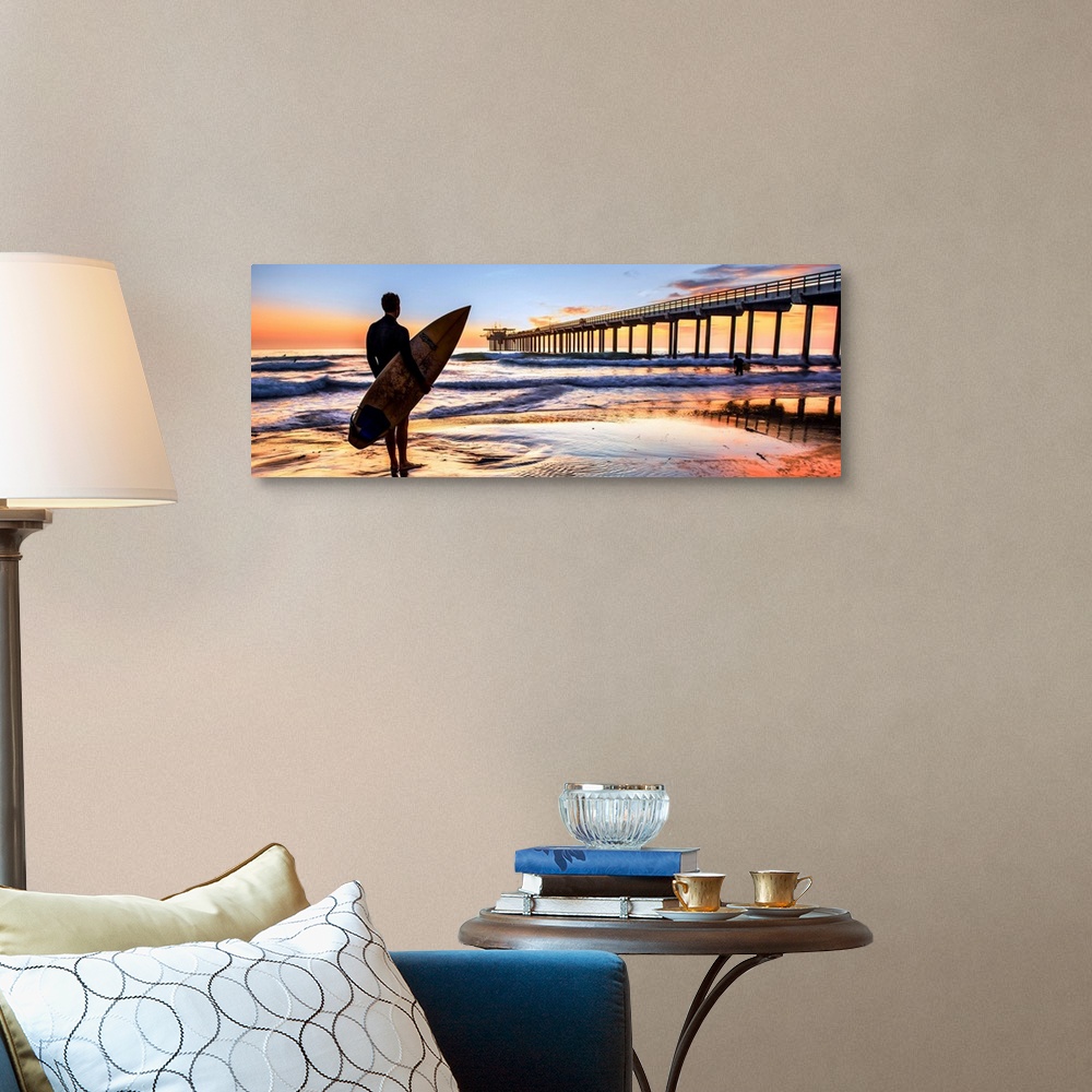 A traditional room featuring Silhouetted panoramic photograph of a man holding a surf board on the shore of Scripps Beach in S...