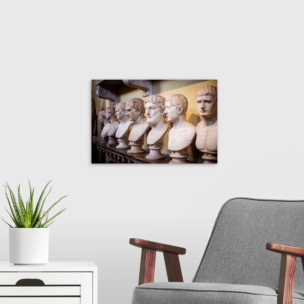 A modern room featuring Photograph of sculptures in a row inside the Vatican History Museum.