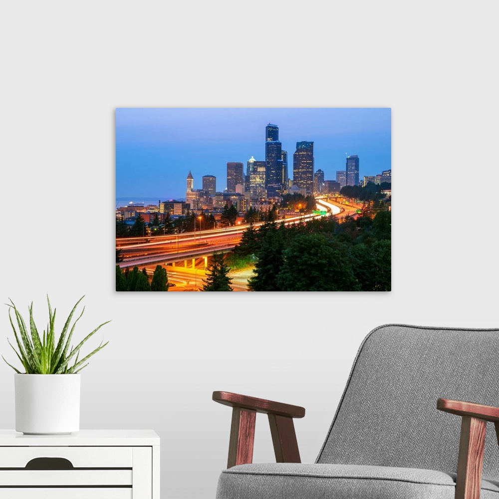 A modern room featuring Photograph of the Seattle skyline at dusk with light trails from the cars on the highway in the f...