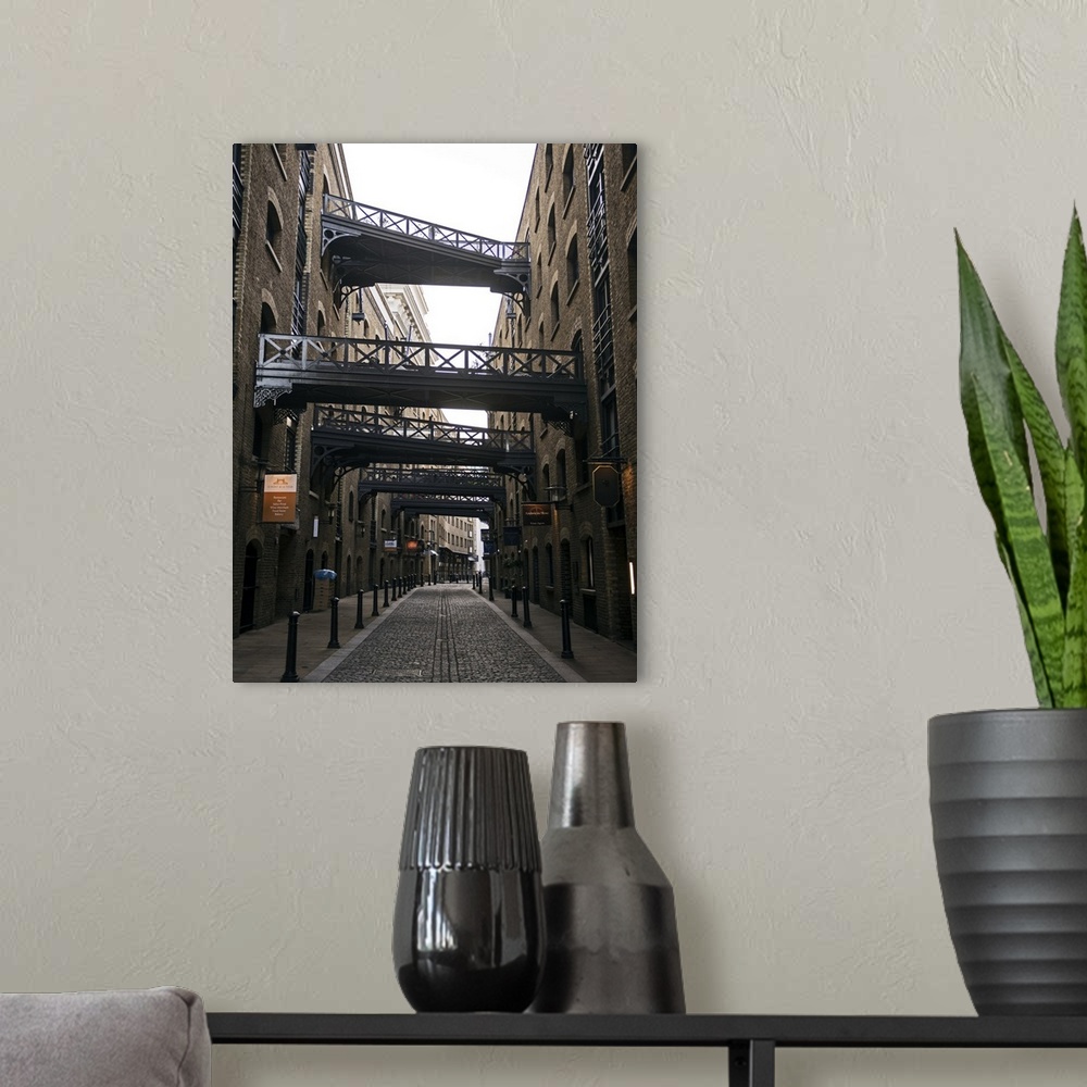 A modern room featuring Photograph of Shad Thames lined with warehouses and walkways alongside Tower Bridge in London.