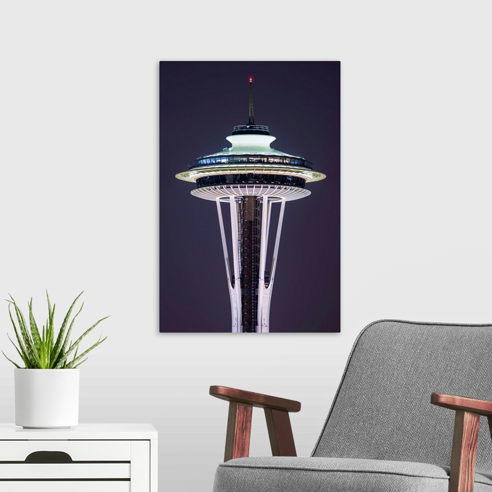 A modern room featuring Photograph of the Seattle Space Needle lit up at night with dark purple skies in the background.
