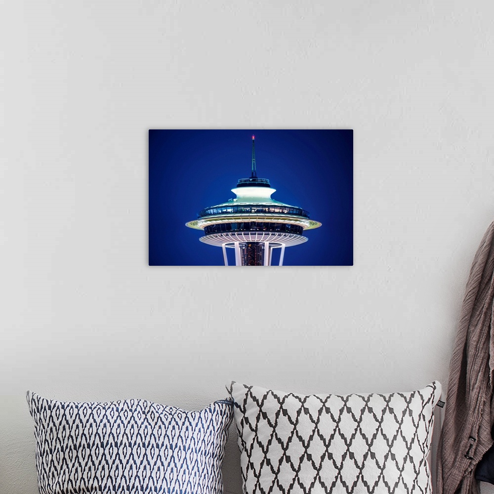 A bohemian room featuring Photograph of the top of the Seattle Space Needle lit up at night on a dark purple sky.