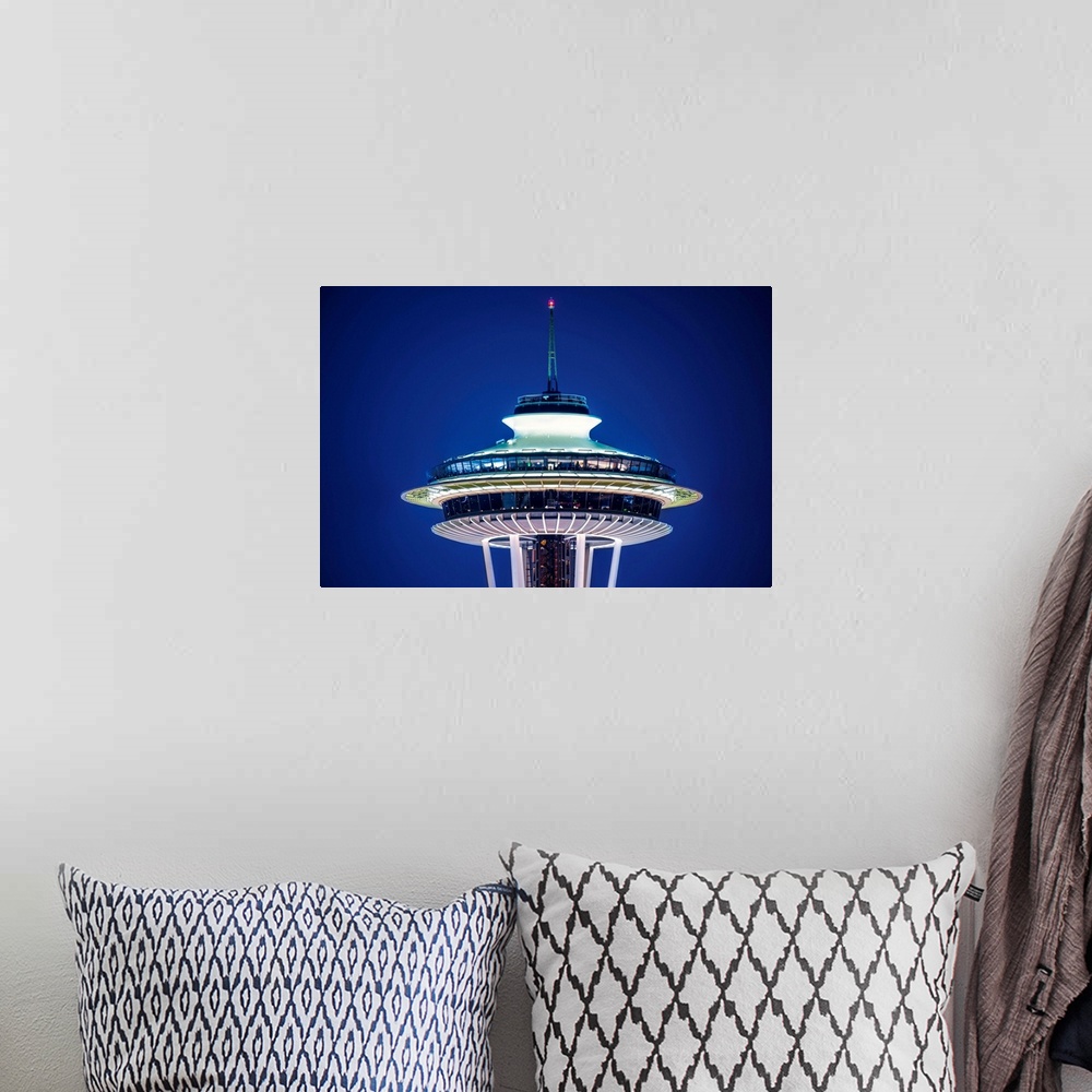 A bohemian room featuring Photograph of the top of the Seattle Space Needle lit up at night on a dark purple sky.