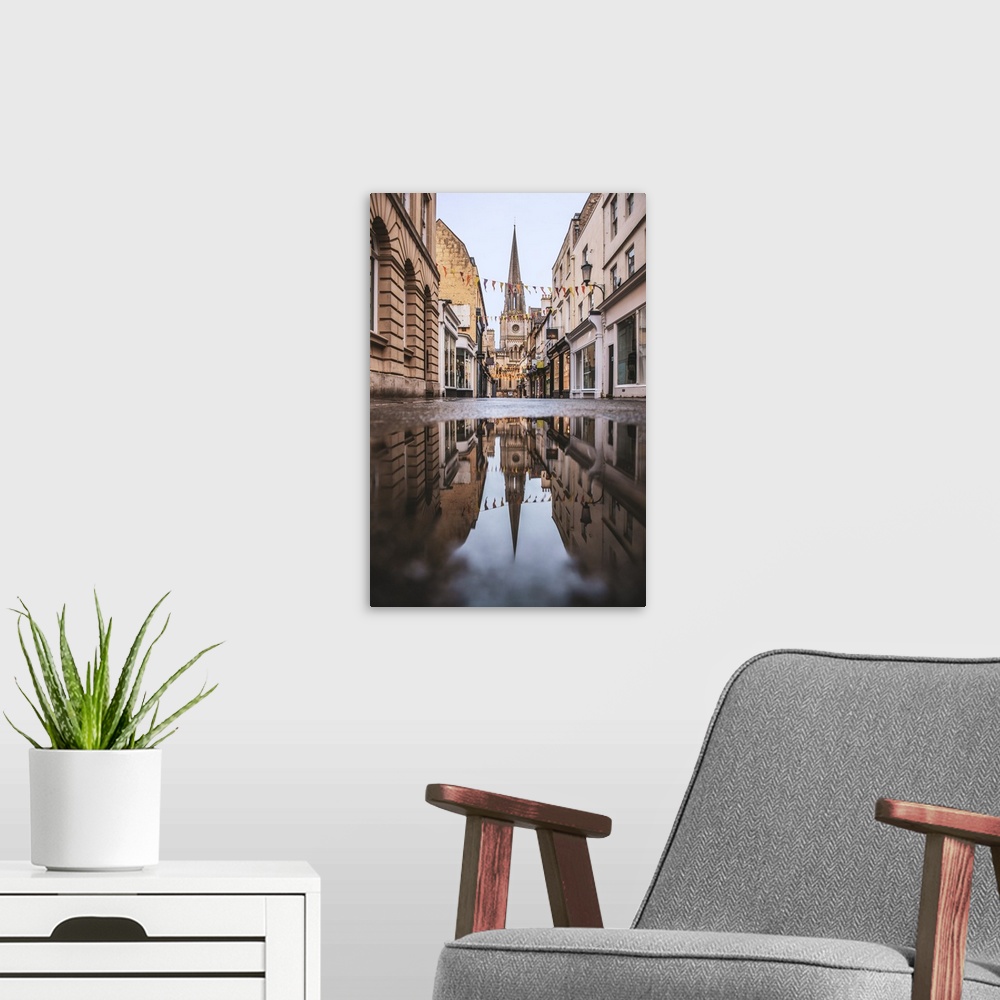 A modern room featuring Photograph of St. Michael's Church reflecting into a puddle in the middle of a street in Bath, En...