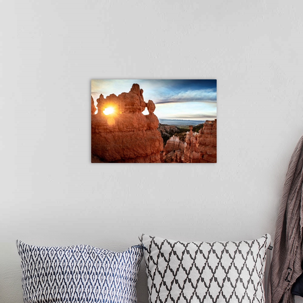 A bohemian room featuring The sun shining through a naturally eroded hole in a hoodoo formation in Bryce Canyon National Pa...