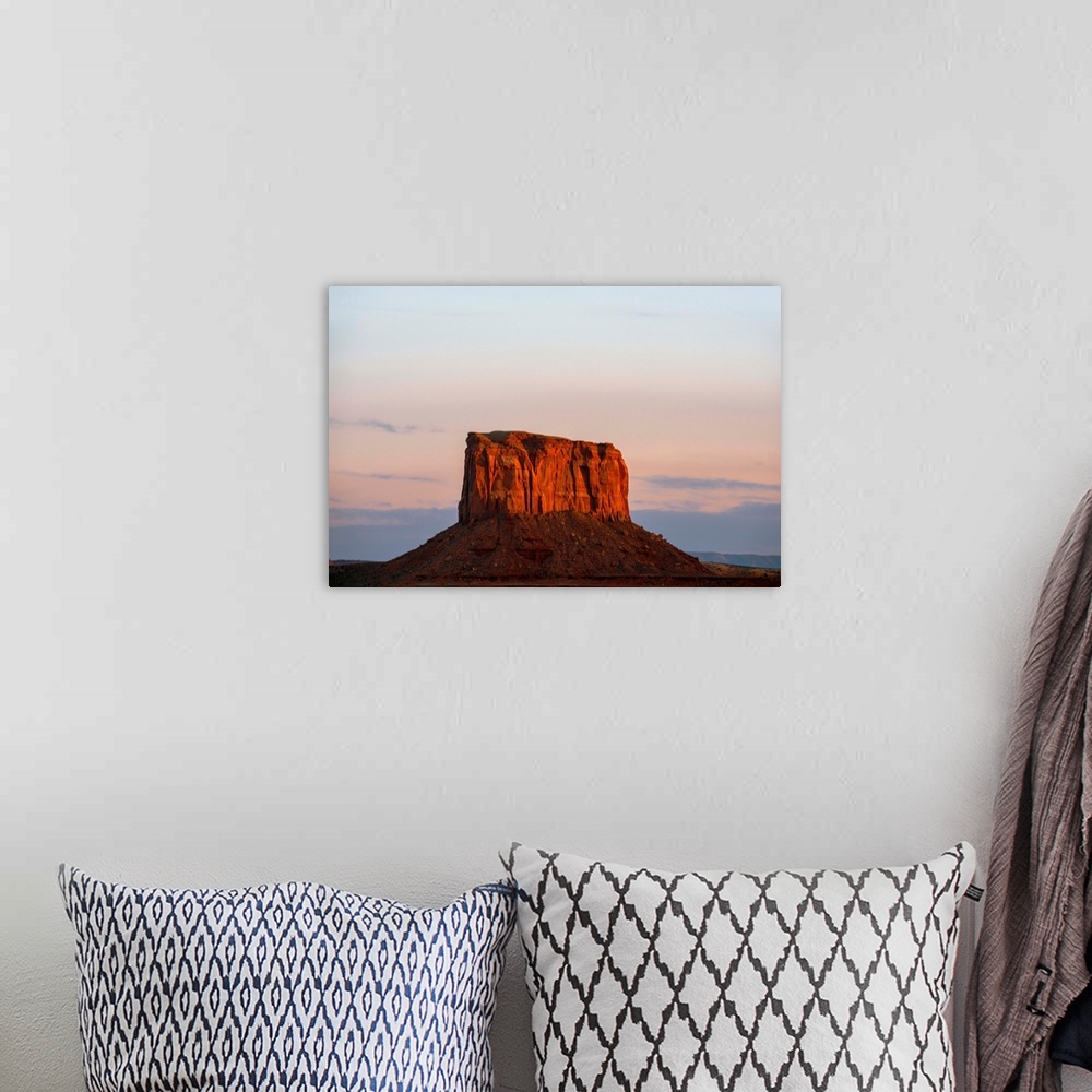 A bohemian room featuring The sun sets on Mitchell Butte, highlighting the rich red sandstone In Monument Valley, Arizona.