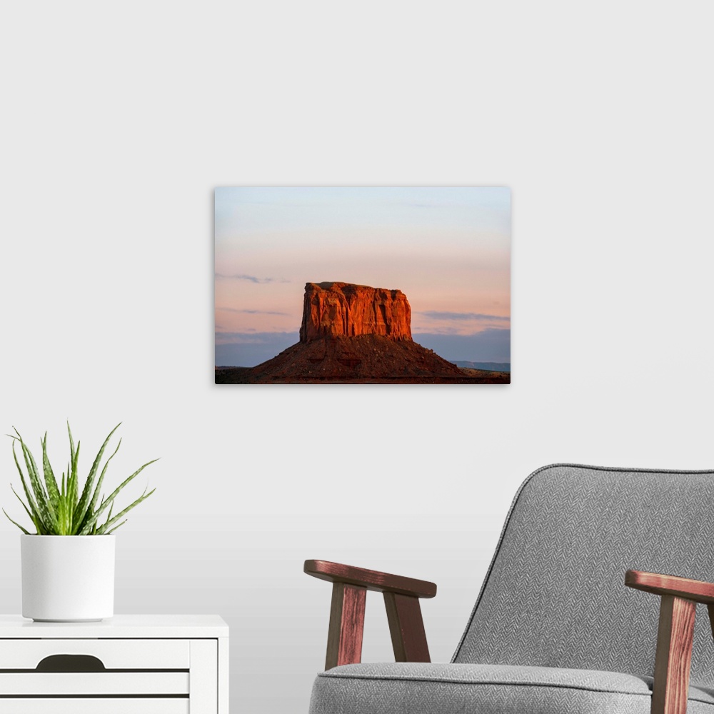 A modern room featuring The sun sets on Mitchell Butte, highlighting the rich red sandstone In Monument Valley, Arizona.