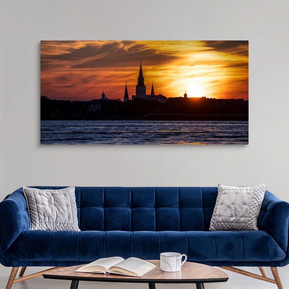 A modern room featuring The sun sets on the Mississippi River with view of the silhouette of St. Louis Cathedral in New O...